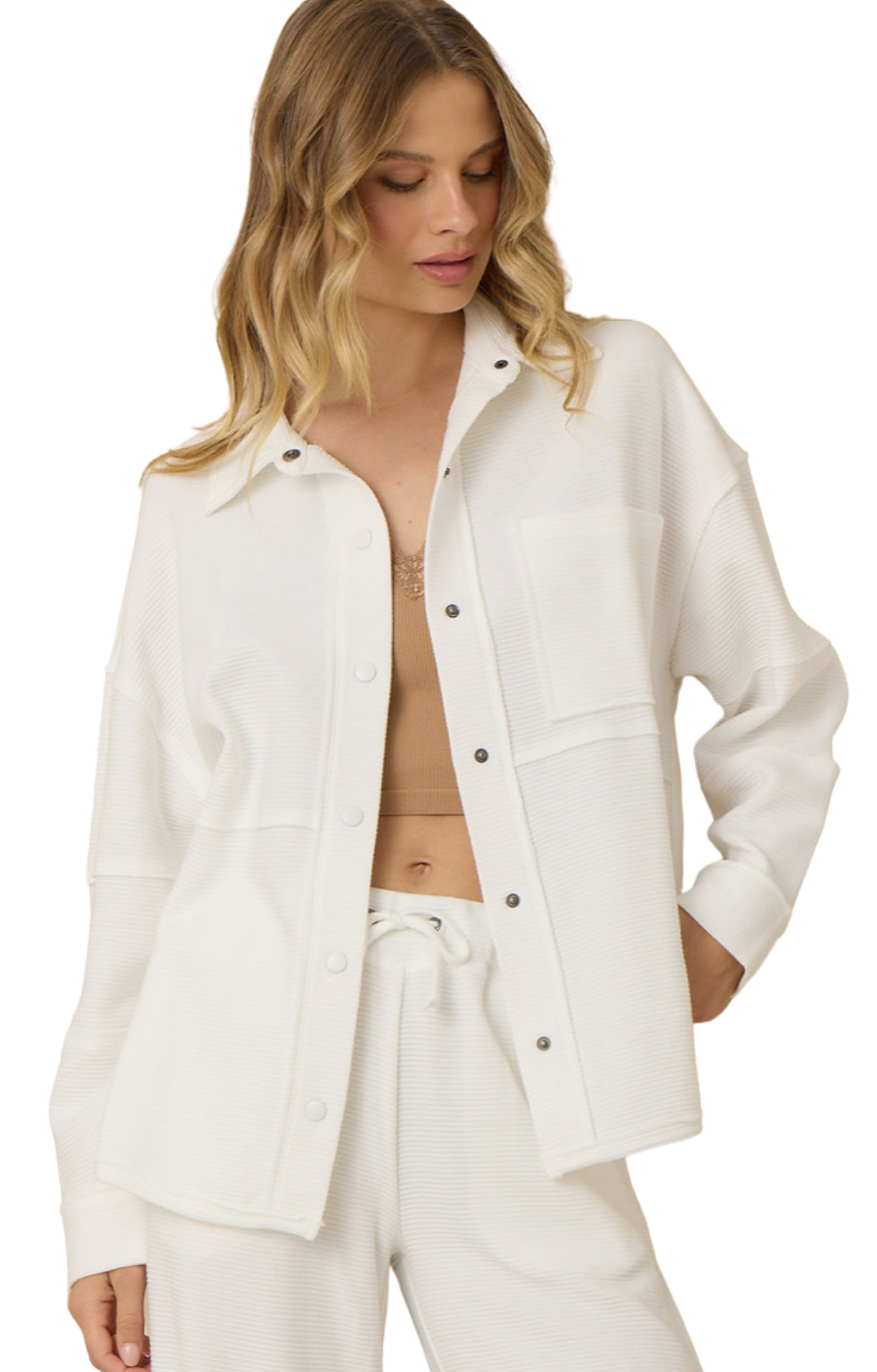 Woman wearing a white button down shacket and pants on a white background