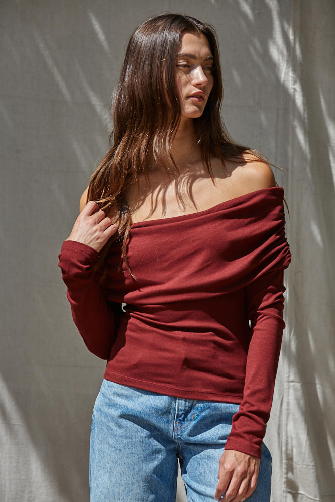 Model wearing a off the shoulder white knit 3/4 sleeve dolman top.
