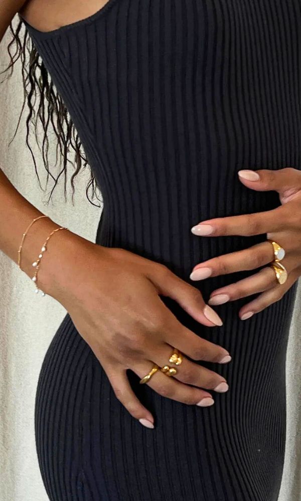 model wearing gold rings and a black dress