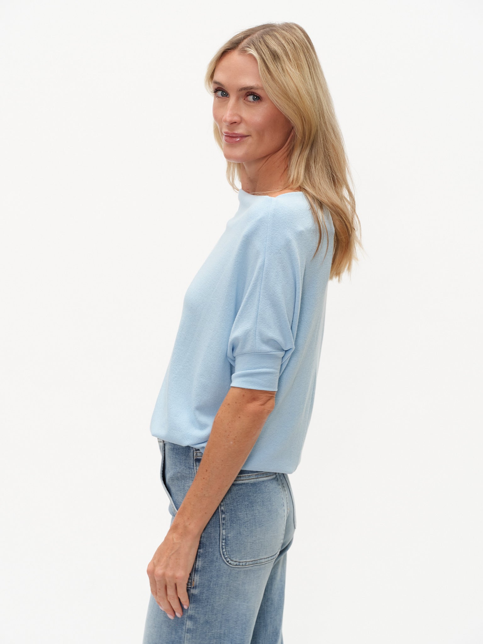 Woman wearing a light blue shirt and jeans on a white background